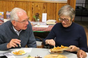 Two people eating South Asian snacks